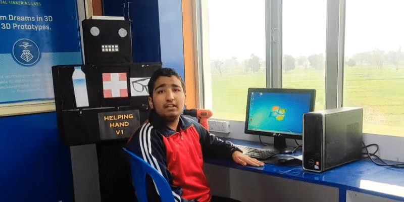 Uplaksh Choudhary with his innovation, the Helping Hand robot, in his tech workspace.