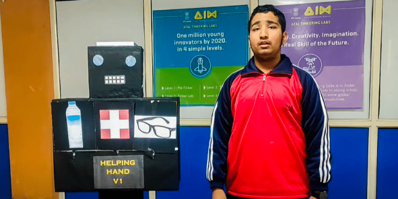 Uplaksh Choudhary stands with his AI robot, Helping Hand, designed to assist seniors.